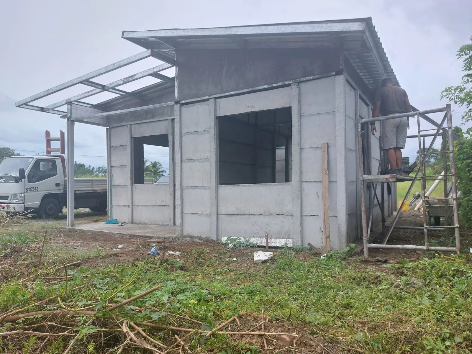 Construcción de casa prefabricada pequeña con muros instalados y operario armando estructura